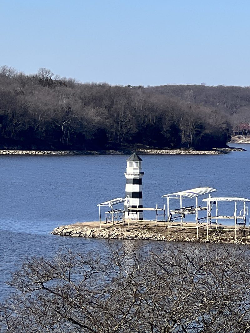 Striped lighthouse on a rocky point with boat lifts at Lake Panorama, Iowa